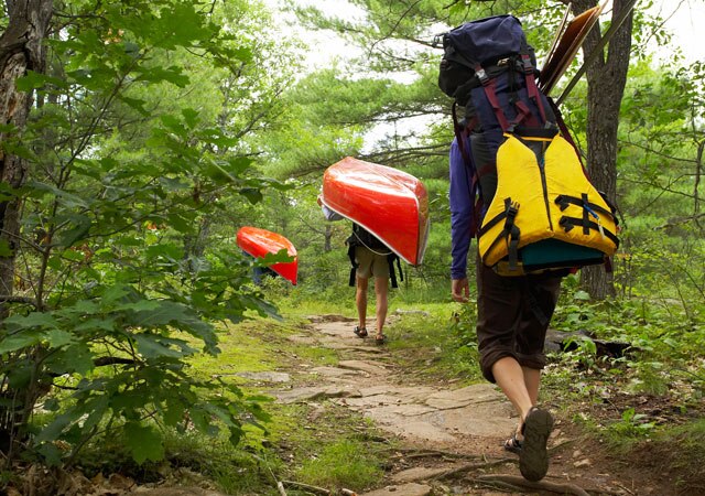 Fotografía de excursionistas cargando una canoa por el bosque Fotografía de excursionistas cargando una canoa por el bosque