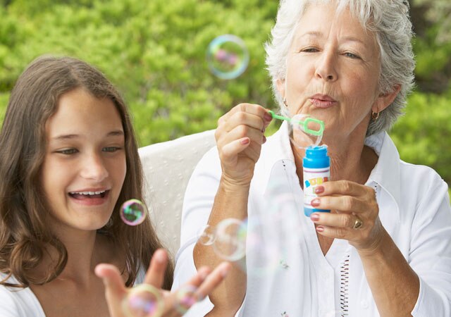 Fotografía de una mujer que sopla burbujas con una niña Fotografía de una mujer que sopla burbujas con una niña