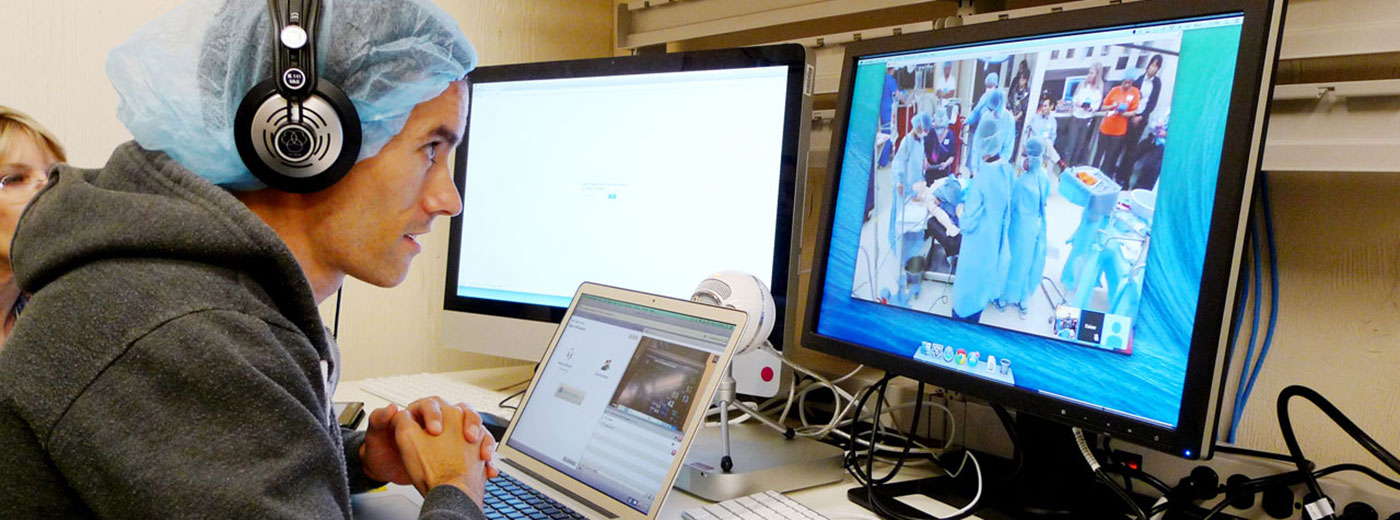Fotografía de un médico en pijama de quirófano y con audífonos usando una computadora Fotografía de un médico en pijama de quirófano y con audífonos usando una computadora