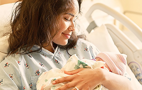 Smiling mother with newborn in arms