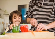 Child and parent chopping vegetables