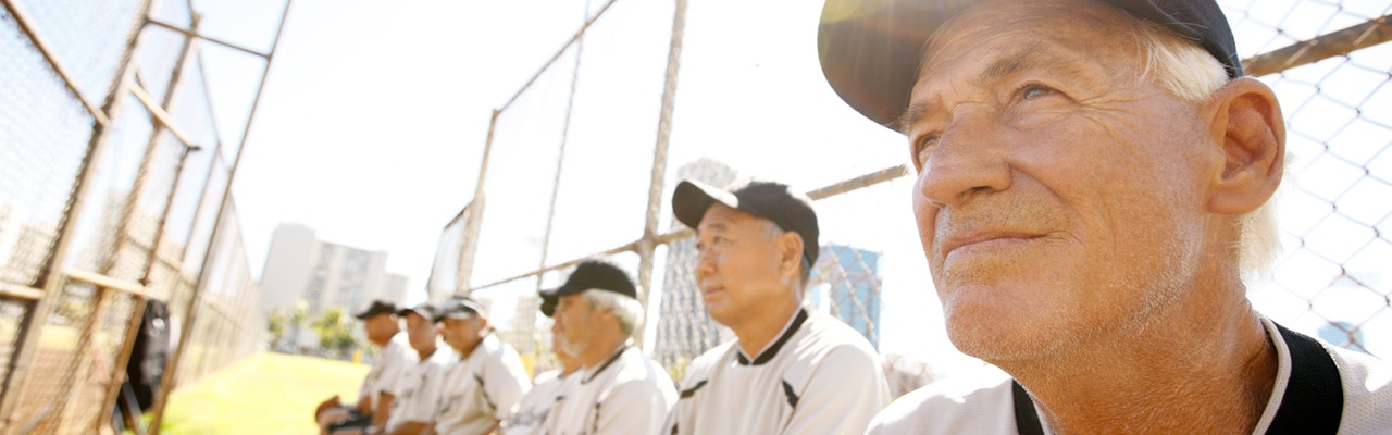 hombres mayores en los uniformes del béisbol que se sientan en un dugout del béisbol