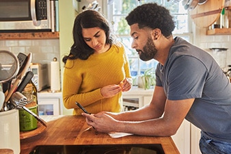 Pareja en la cocina mirando un teléfono inteligente