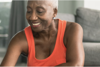 Una persona de edad avanzada sonríe mientras se sienta en un tapete de yoga