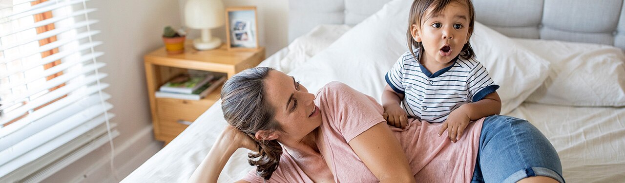 Padre y bebé felices sentados sobre una cama