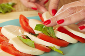 Una persona colocando tomates y queso en un plato