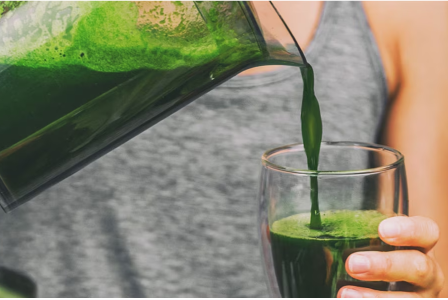 Una persona sirviendo jugo verde en una taza