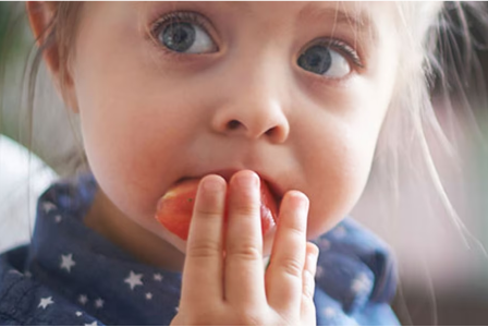 Un niño comiendo brócoli y tomates de un plato