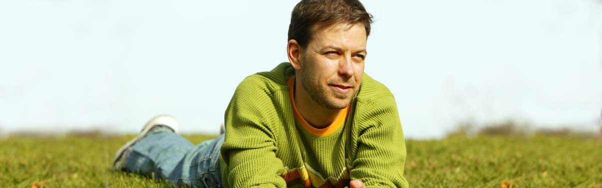 Man laying on the grass looking thoughtful