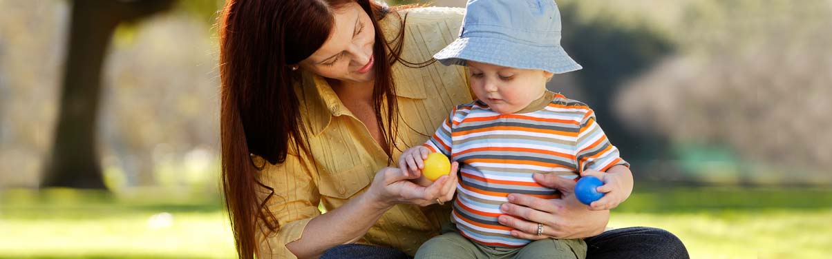 Mamá que sostiene a su bebé mientras juegan al aire libre