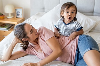 Madre y bebé jugando sobre una cama