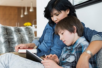 Madre mirando a su hijo que está usando una tableta