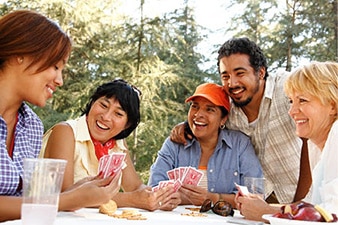 Grupo de amigos sonrientes jugando a las cartas al aire libre