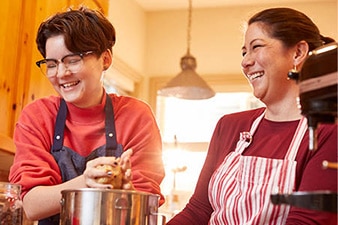 Adolescente y mamá sonrientes horneando juntos en la cocina