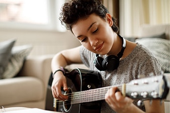 Adolescente sonriendo y tocando la guitarra