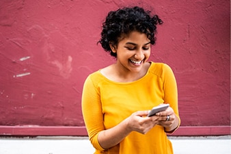 Adolescente sonriendo mientras usa su teléfono celular