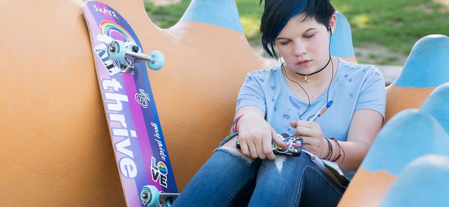 Mujer adolescente con cabello azul y patineta escribiendo en un diario Mujer adolescente con cabello azul y patineta escribiendo en un diario