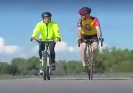 two men talk and ride bicycles