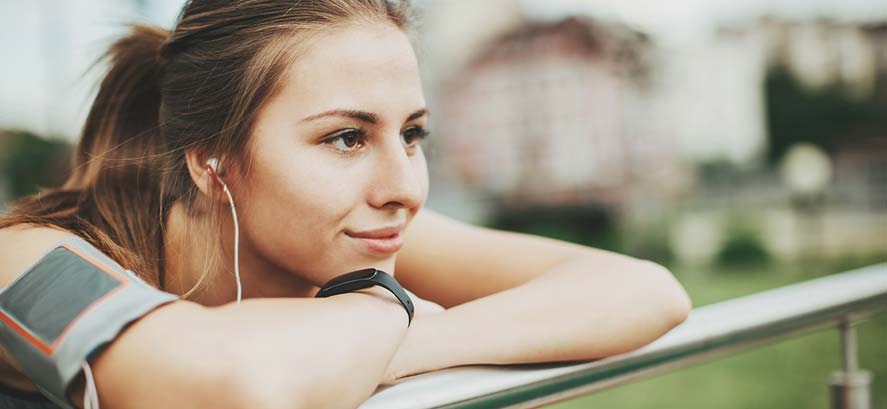 Woman listening to headphones leaning on rail Woman listening to headphones leaning on rail
