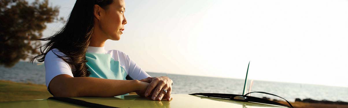 Woman with a surfboard looking at the ocean