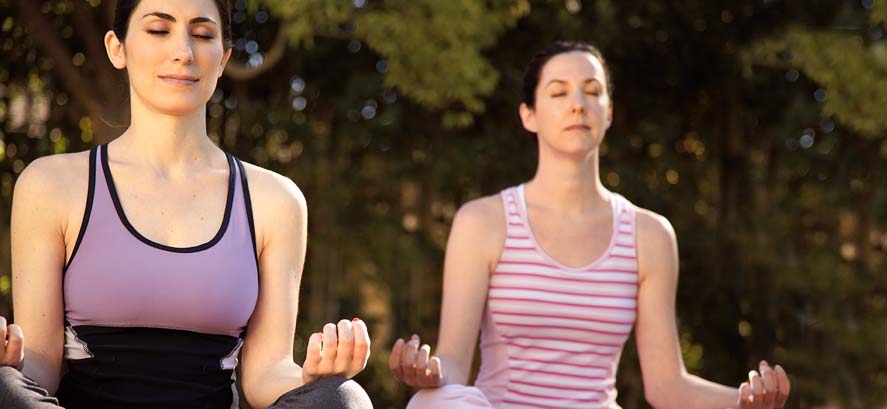Women doing yoga and meditating outdoors
