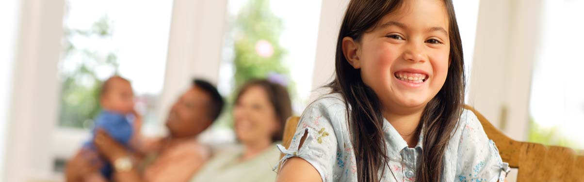 Young girl smiling at table with family in background