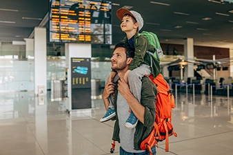 Padre cargando a su hijo pequeño sobre los hombros en un aeropuerto