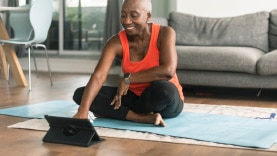 Persona sentada en un tapete de ejercicio mientras configura su tableta.