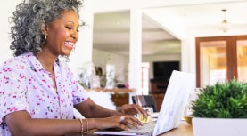 smiling woman types on laptop