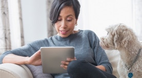 woman uses tablet with dog