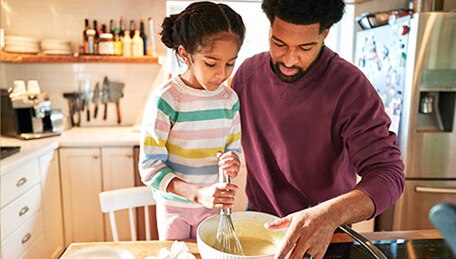 Persona e hijo preparando la comida juntos en casa