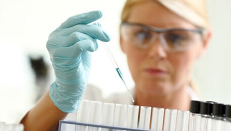 Persona que trabaja en el laboratorio introduciendo líquido en frascos