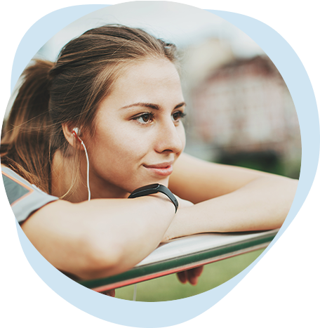 Mujer que escucha con audífonos apoyada en una baranda