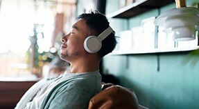Persona adulta con auriculares reclinada con los ojos cerrados