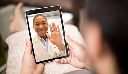 Médico en la pantalla saludando a la persona que sujeta la tableta