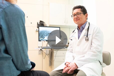 Video play button over image of Kaiser Permanente Colorado doctor talking with patient