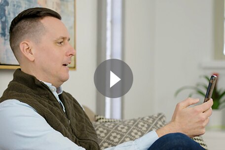 Video play button over image of Kaiser Permanente Colorado member using a health monitoring app on smart phone