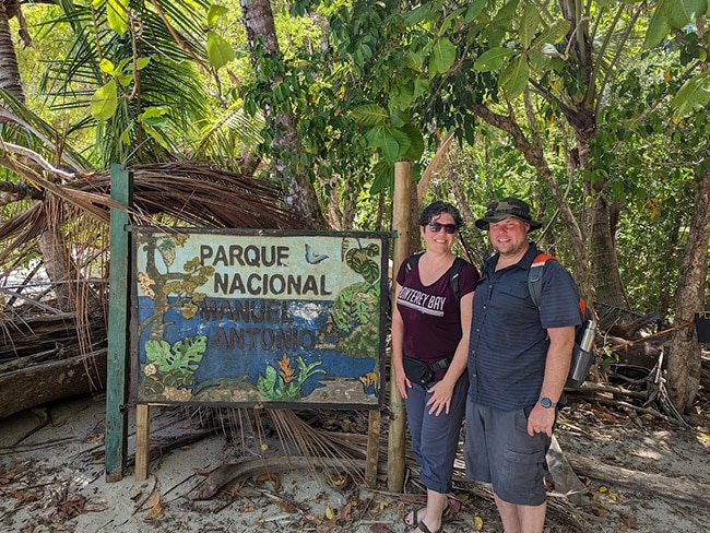 Una pareja junto a un gran cartel en un parque nacional de Costa Rica.   