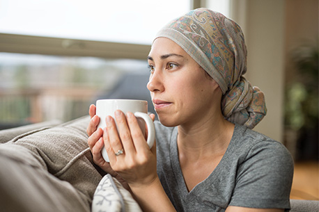 Persona sentada junto a una ventana bebiendo de una taza