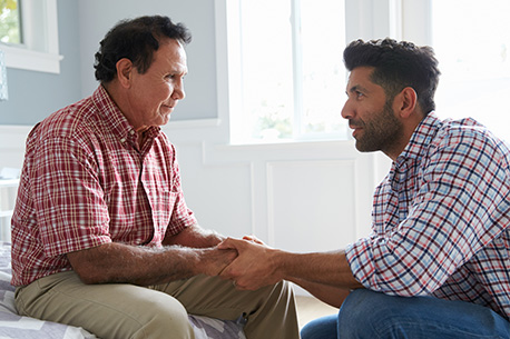 Padre e hijo adulto tomados de la mano