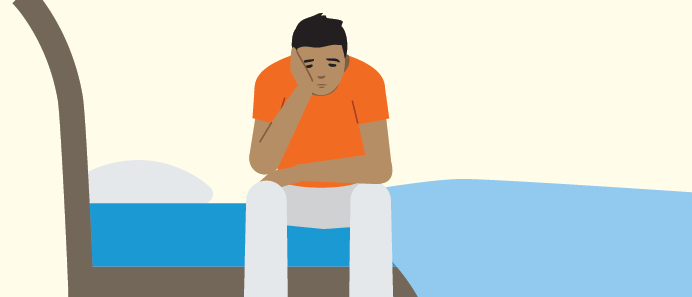 Adolescente sentado en una cama con cara triste