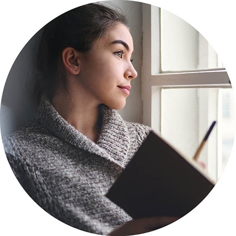 Persona sentada en un alféizar escribiendo en un cuaderno