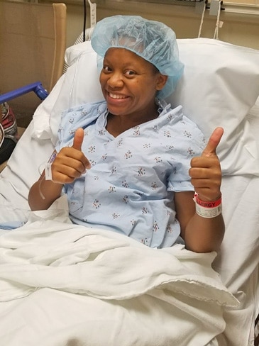 Kaiser Permanente member Tasha Champion smiles and gives 2 thumbs up from her hospital bed. 