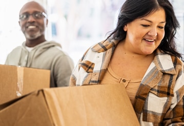 Unas personas sonríen mientras sostienen unas cajas