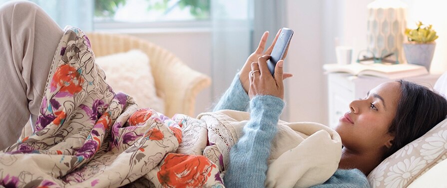 Persona en la cama mirando su teléfono inteligente