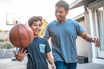 Niño feliz con su pelota de baloncesto mientras camina con su padre