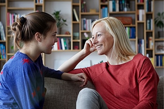 Persona adulta hablando con una adolescente en un sofá