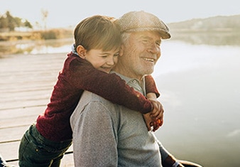 Nieto que abraza a su abuelo junto a un lago