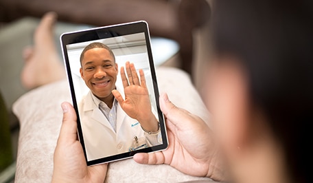 Persona haciendo una consulta virtual con su médico en una tableta